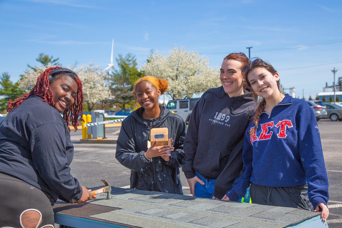 group of happy students repairing roof