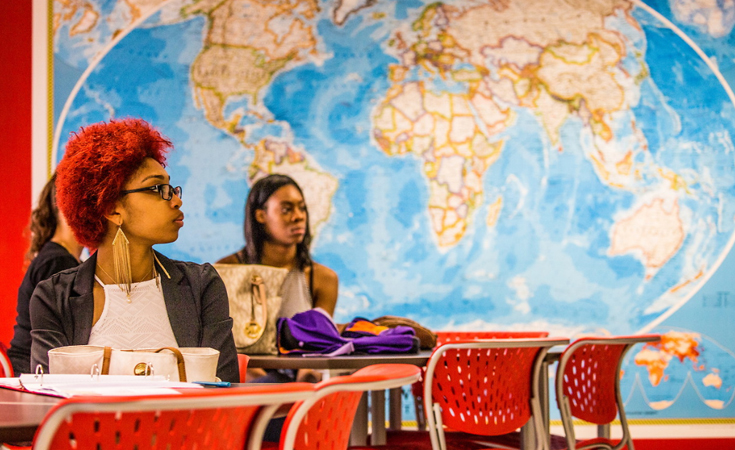 female students in front of large world map