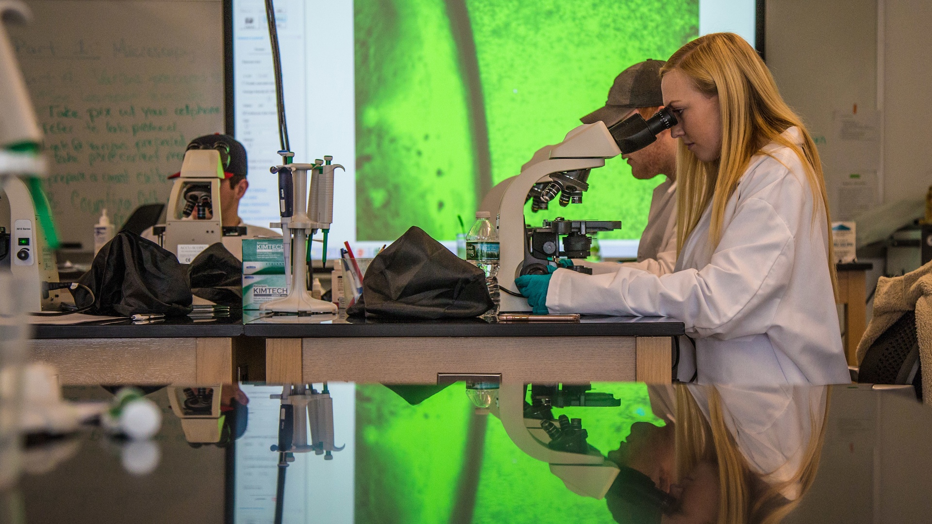 students in lab looking through microscope