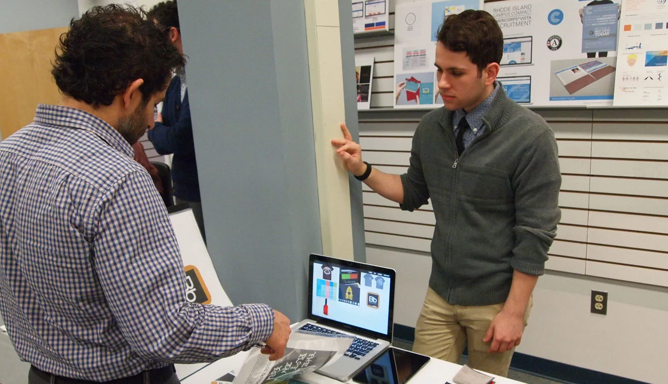 Professor Jeff Drury flips through a student portfolio at JWU Providence’s School of Engineering & Design.
