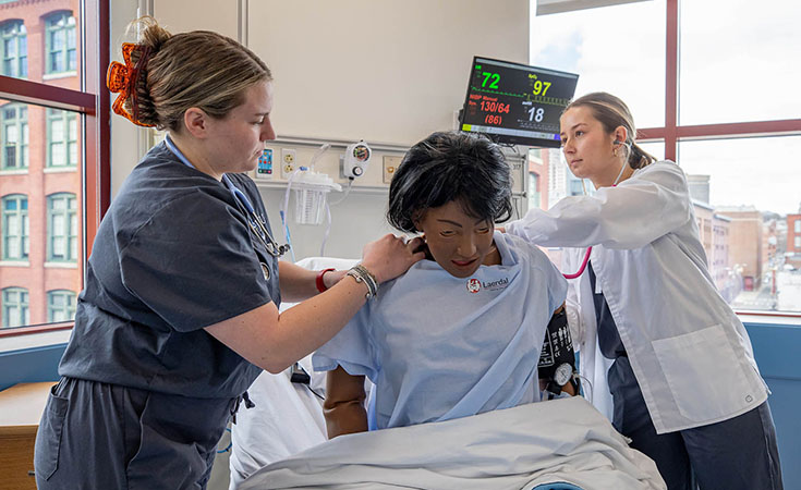 nursing students working with practice dummy in lab