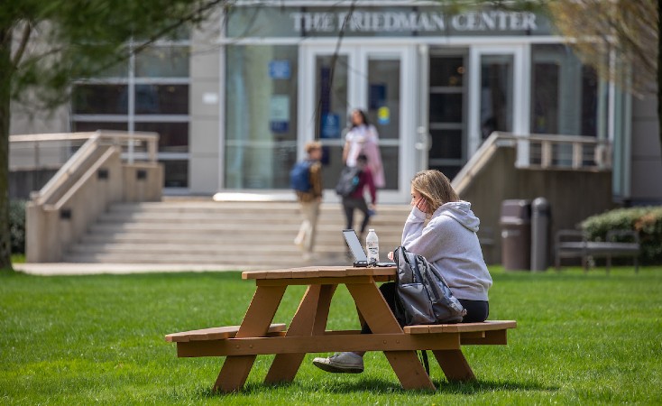 Student at picnic bench outside of The Friedman Center